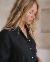 Vestido camisero de lino color marrón, de corte recto y largo midi, con mangas largas abotonadas, cuello camisero y cierre frontal con botones de nácar.