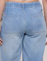 Pantalón tipo jean de corte relajado y pierna ancha, color celeste, con pretina elástica en la espalda, cordón de ajuste frontal y dobladillo en los tobillos.