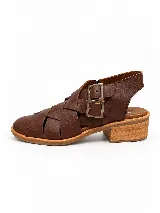 Sandalia de cuero marrón con diseño de tiras anchas entrelazadas, taco bajo de madera y hebillas metálicas laterales.