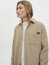 Sobrecamisa de manga larga confeccionada en pana, con cuello camisero, cierre frontal de botones, puños abotonados y un bolsillo en el pecho con etiqueta de marca. Presenta un corte relajado y textura acanalada.