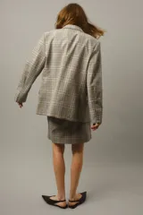 Blazer cruzado de sarga de algodón con estampado a cuadros en tonos beige, azul y marrón. Presenta solapas de pico, botones forrados, hombreras, un bolsillo superior insertado y dos bolsillos ribeteados con solapa. Las mangas tienen botones de cascada en los puños y cuenta con una abertura doble en la parte trasera.