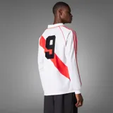 Camiseta de fútbol Adidas de manga larga de River Plate, modelo retro inspirado en 1994. Diseño en color blanco con la tradicional banda roja diagonal, cuello polo, y detalles en rojo en los hombros y las icónicas tres tiras en las mangas.