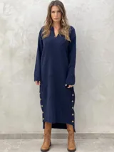 Vestido midi de punto color azul marino, con cuello en V, mangas largas y diseño holgado. Presenta un patrón de rombos en relieve y aberturas laterales con botones decorativos en el ruedo.