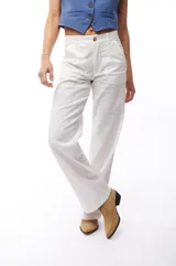 Pantalón blanco de corte recto, con bolsillos laterales y traseros. Se ajusta a la cintura con cinturón de cuero marrón.