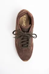 Zapatilla de estilo urbano confeccionada en cuero legítimo y gamuza en tono marrón, con diseño de costuras decorativas laterales y suela plana de goma.