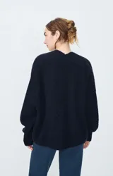 Cárdigan corto de punto color negro, con mangas largas y corte holgado.