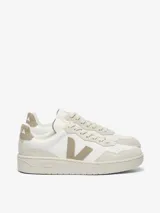 Championes Veja modelo V-90, de diseño urbano con silueta de perfil bajo. Confeccionados en cuero blanco con detalles en gamuza color beige en los laterales, talón y puntera. Presentan suela plana de goma y cierre con cordones.