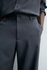 Pantalón de corte relaxed fit, con cintura ajustable, bolsillos delanteros y bolsillo trasero de plastrón. Presenta cierre frontal con cremallera y botón.