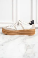 Zapatillas bajas de cuero color blanco y beige, con suela gruesa marrón y cordones blancos.