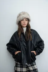 Chaqueta de cuero sintético color marrón con capucha y solapas amplias en tela escocesa a cuadros. Posee cierre frontal, puños elásticos y diseño de corte holgado.