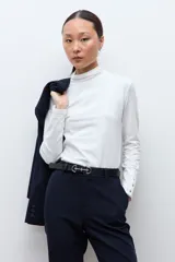 Media polera de manga larga con cuello alto y detalle de frunces en los puños, confeccionada en tejido suave y elástico.