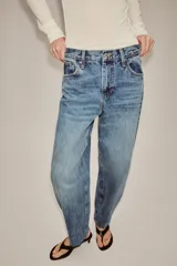 Jeans de tiro alto con corte tapered y largo al tobillo. Presenta cinco bolsillos, trabillas en la cintura, cierre frontal con cremallera y botón, y detalle de raya planchada en el delantero.