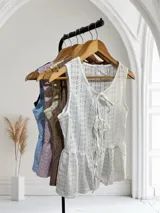 Blusa sin mangas de encaje con detalle de lazo en el escote y corte peplum.