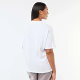 Remera blanca de corte oversize y manga corta, con estampa frontal en tonos azules y amarillos que incluye el texto 'Costa Azul' y 'Palma de Mallorca'.
