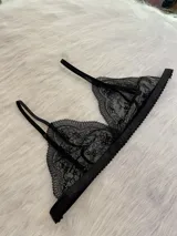 Conjunto de lencería de tres piezas en encaje negro. Incluye bralette con breteles regulables y collarín integrado, y tanga regulable con corte media less.
