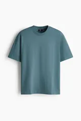 Remera de manga corta color verde, confeccionada en punto liviano, con cuello redondo ribeteado, hombros caídos, bajo recto y corte relajado.