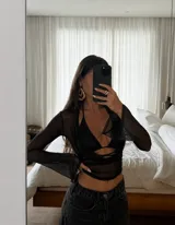 Top negro de tela translúcida con mangas largas acampanadas y diseño cruzado, acompañado de un top interior tipo bralette con tiras finas y escote en V.