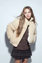 Campera puffer de corderito negro con cuello alto y diseño oversized. Presenta una textura tipo teddy, cierre frontal y corte a la cintura.