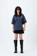 Remera negra de corte holgado con mangas cortas amplias y cuello redondo. Estampado pequeño de flor en el pecho y estampado grande en la espalda con diseño floral y texto.