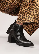 Botín negro de cuero con elástico lateral y cierre interno. Tiene plataforma delantera de 2 cm y taco de 8 cm.