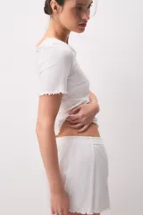 Short de pijama blanco de 100% algodón, con diseño texturado a rayas verticales, cintura elástica con botones decorativos y detalles de ondas en el ruedo.