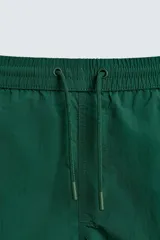 Bañador de hombre color azul marino, confeccionado en tejido técnico, con cintura elástica ajustable mediante cordón. Presenta bolsillos laterales y un bolsillo trasero de plastrón. Incluye forro interior.