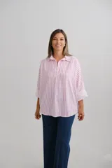 Blusa de corte holgado con estampado de rayas verticales en color fucsia y blanco. Presenta cuello camisero con escote en V y mangas largas con puños vueltos.