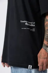 Remera blanca de corte oversize con cuello redondo y mangas cortas. Presenta un pequeño estampado tipográfico en la parte inferior frontal y un diseño gráfico de mayor tamaño en la espalda.