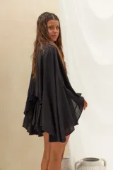Set de blusa estilo capa de corte holgado con mangas amplias y short con volados y cordón ajustable en la cintura, confeccionado en lino color negro.