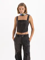 Top de gabardina con efecto batik, corte ajustado al cuerpo y largo hasta la cintura. Presenta escote cuadrado con detalle de volados en cuero vacuno, breteles anchos y apliques de remaches metálicos en forma de flor en el frente.