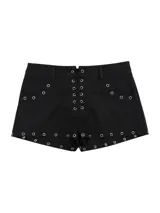 Short negro de tiro medio con cordones entrecruzados en la parte frontal, decorado con múltiples ojales metálicos en los bolsillos y en todo el ruedo.