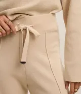 Pantalón wide leg de punto con textura acanalada, cintura elástica con lazo ajustable y detalles metalizados, y frisos verticales a lo largo de la pierna.