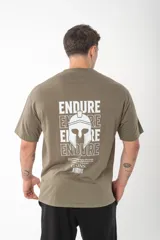 Remera de algodón color verde oliva, con corte oversize y estampado gráfico en la espalda que incluye un casco espartano y la palabra 'ENDURE'.