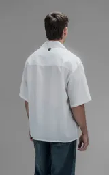 Camisa de manga corta con cuello cubano, corte oversize y cierre frontal de botones. Confeccionada en tejido de lyocell, presenta un diseño minimalista y liso.