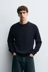 Sweater de punto en canalé color negro, de corte regular fit, cuello redondo y manga larga con terminaciones en rib.
