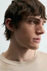 Camiseta de punto de algodón con corte relajado (relaxed fit) y cuello redondo. Presenta un estampado frontal con efecto spray en tonos marrones y beige, y un efecto lavado general.