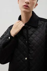 Campera acolchada de corte holgado, color blanco con diseño capitoneado en forma de rombos. Presenta cuello camisero y bordes internos con estampado floral en tonos azul y rojo, cierre frontal con botones a presión y bolsillos laterales.