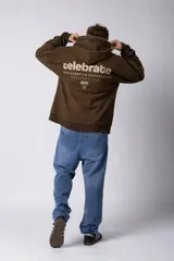 Buzo tipo canguro con capucha, de corte oversize y confeccionado en frisa rústica con efecto lavado. Presenta bolsillo frontal tipo canguro y estampado con texto en el pecho.