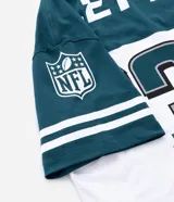 Remera de corte oversized con diseño deportivo de los Philadelphia Eagles. Presenta cuello redondo, mangas cortas con detalles de rayas y estampa frontal del equipo. Confeccionada en algodón.