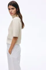 Top de punto suave con lana, de manga corta, con cuello alto acanalado y terminaciones acanaladas en puños y bajo.