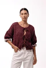 Saco de punto gris con frente abierto y cierre mediante lazos frontales. Presenta mangas abullonadas con puños elásticos y un diseño de textura voluminosa.