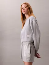Buzo cropped de cuello redondo, confeccionado en algodón regenerativo, con puños y dobladillo en punto canalé y detalle de insignia con logotipo de la marca.