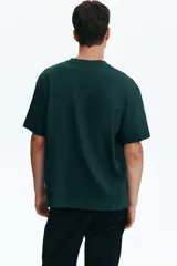 Remera en punto de algodón verde oscuro, con cuello redondo ribeteado, hombros caídos, mangas cortas y bajo recto de corte relajado.