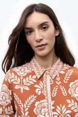 Camisa de manga larga con estampado floral en tonos ladrillo y blanco, con cuello camisero y cierre frontal de botones.