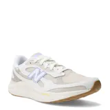 Championes de running New Balance modelo Fresh Foam Arishi V4, color beige con detalles en lila y suela de goma color caramelo. Presentan diseño de malla transpirable con refuerzos sintéticos y tecnología de amortiguación Fresh Foam en la entresuela.