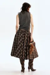 Chaleco de punto gris oscuro, sin mangas, con cuello camisero y tapeta de botones. Presenta un acabado de punto acanalado en las sisas y el bajo.