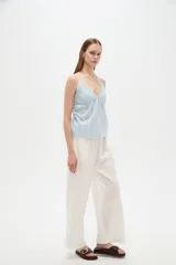 Musculosa blanca de algodón con diseño de broderie, escote en V, tirantes finos regulables y corte holgado.