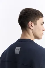 Buzo de algodón color marrón chocolate, con cuello redondo, mangas largas y estampa frontal con el nombre de la marca repetido en tono sobre tono.