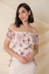 Vestido largo de tul bordado en color rosado, con flores bordadas en tonos fucsia y rosado en la parte superior, tajo lateral y mangas caídas.