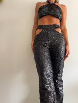 Pantalón de lentejuelas negro con aberturas en la cadera y corte recto.
